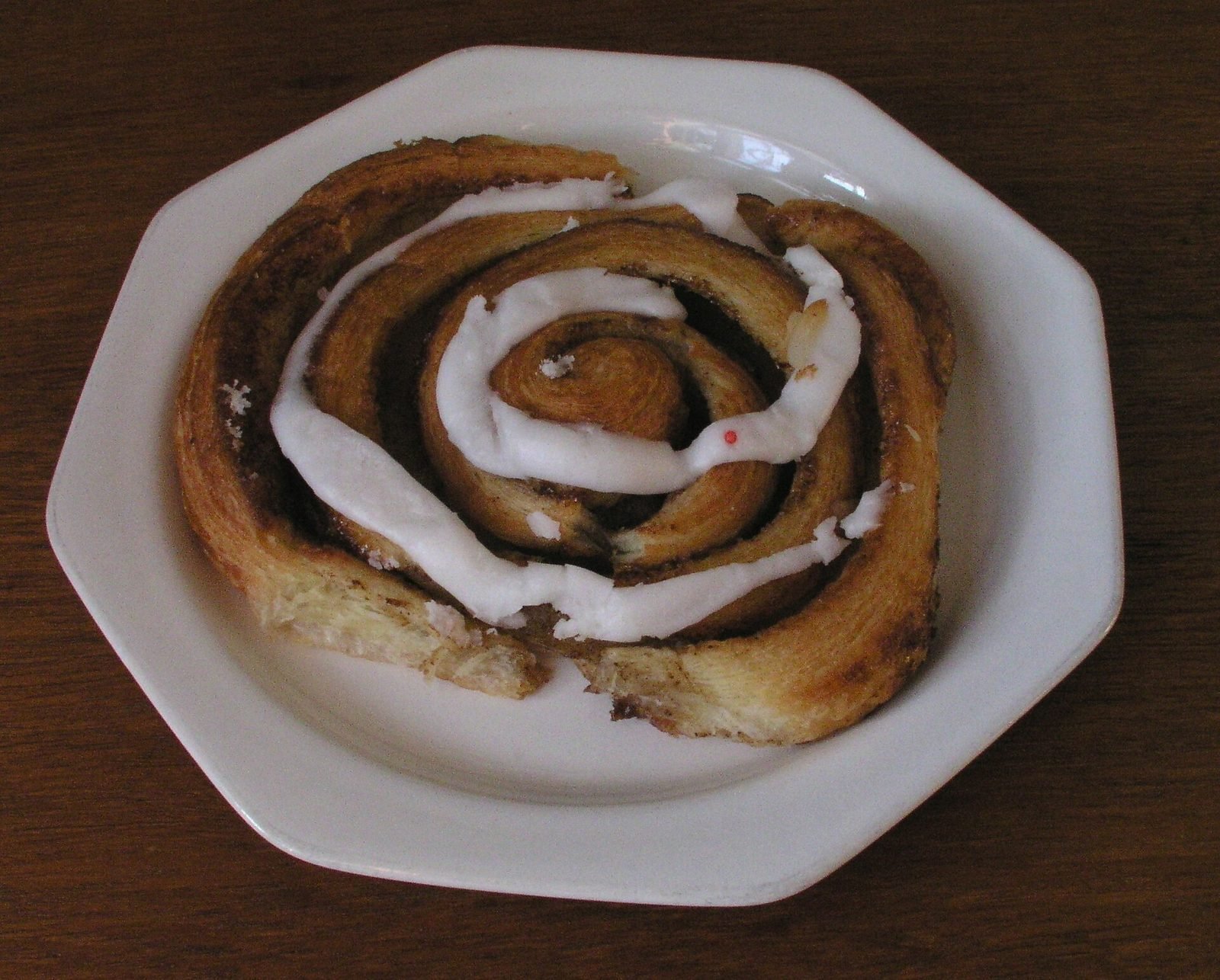 Dansk kanelsnegl med glasur p&aring; en hvid tallerken